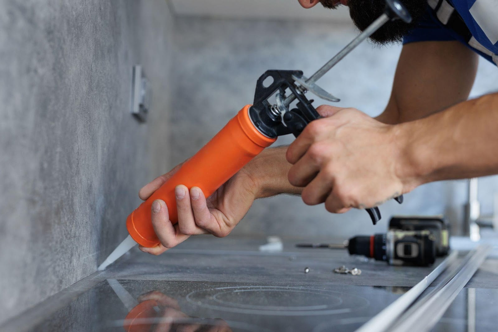 A man using an orange tool to repair a sink