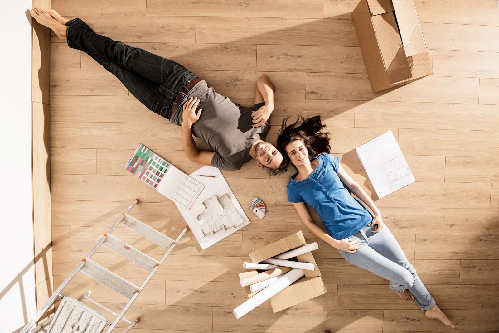 A couple laying on hardwood flooring with boxes and papers in Utah.